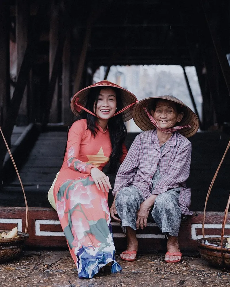 Hai người phụ nữ hai thế hệ đội nón lá cười tươi