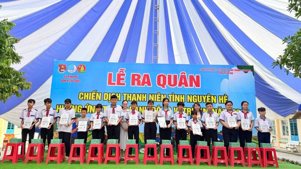 Học sinh nhận quà trên sân khấu Lễ ra quân ở Định Mỹ, An Giang