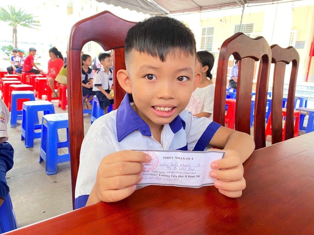 Một em học sinh cầm phiếu nhận quà tại buổi trao quà ở Định Mỹ, An Giang