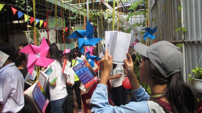 Sinh viên đứng đọc sách treo dưới giàn hoa tại ngày hội sách cuối năm 2016